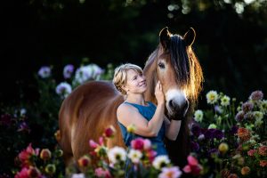 Equestrian and her horse standing in a field of flowers